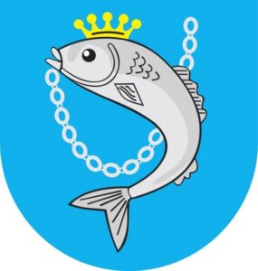  Herb Mikołajek przedstawia srebrną rybę z koroną na głowie, skutą łańcuchem
